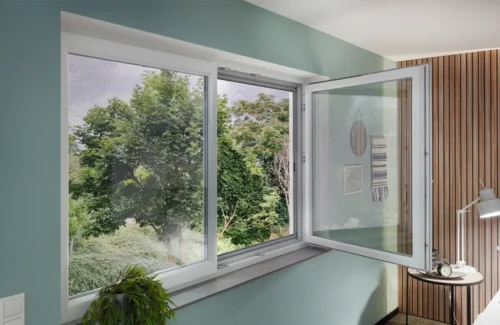 Blick ins Grüne vom Schlafzimmer aus nach draussen durch geöffnetes zweiflügeliges Fenster