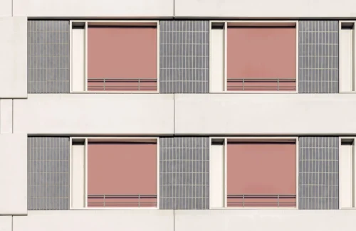Moderne Fassade mit rosa Fensterläden und geometrischen Mustern